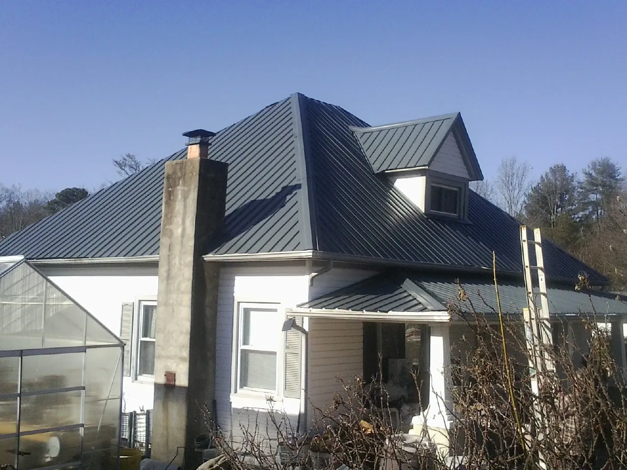 Dark blue standing seam metal roof on a white farmhouse with dormer — Slate & Tile Roof Repair by Roofing Brothers in Paint Lick