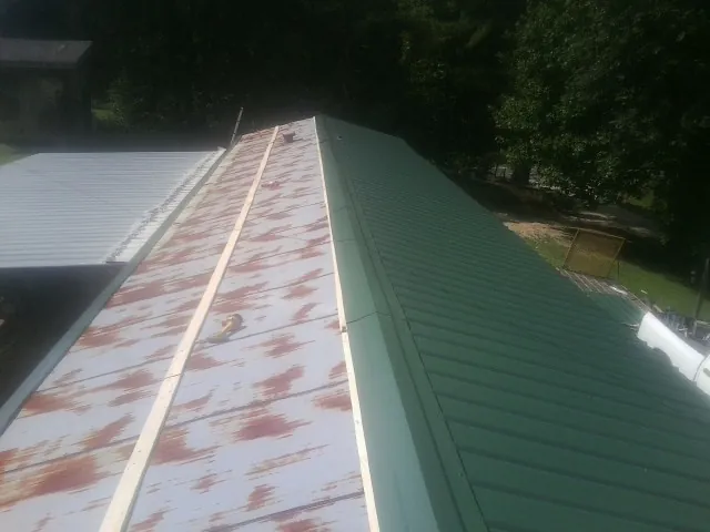 Old rusted panels beside newly installed green metal roofing — Wind Damage Roof Repair by Roofing Brothers in Paint Lick