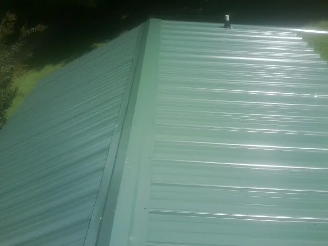 New green metal panels meeting at the ridge of a roof — Flat Roof Repair work by our crew in Paint Lick