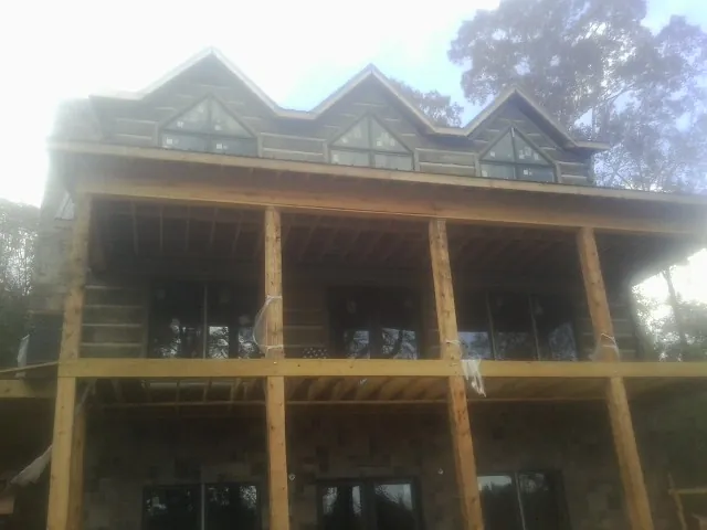 Dormers and porch framing on a large log home under construction — Roof Coating work by our crew in Paint Lick