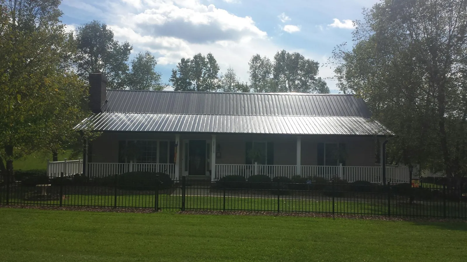 Gray metal roof on a brick ranch with a full width front porch — Gutter Guard Installation work by our crew in Paint Lick