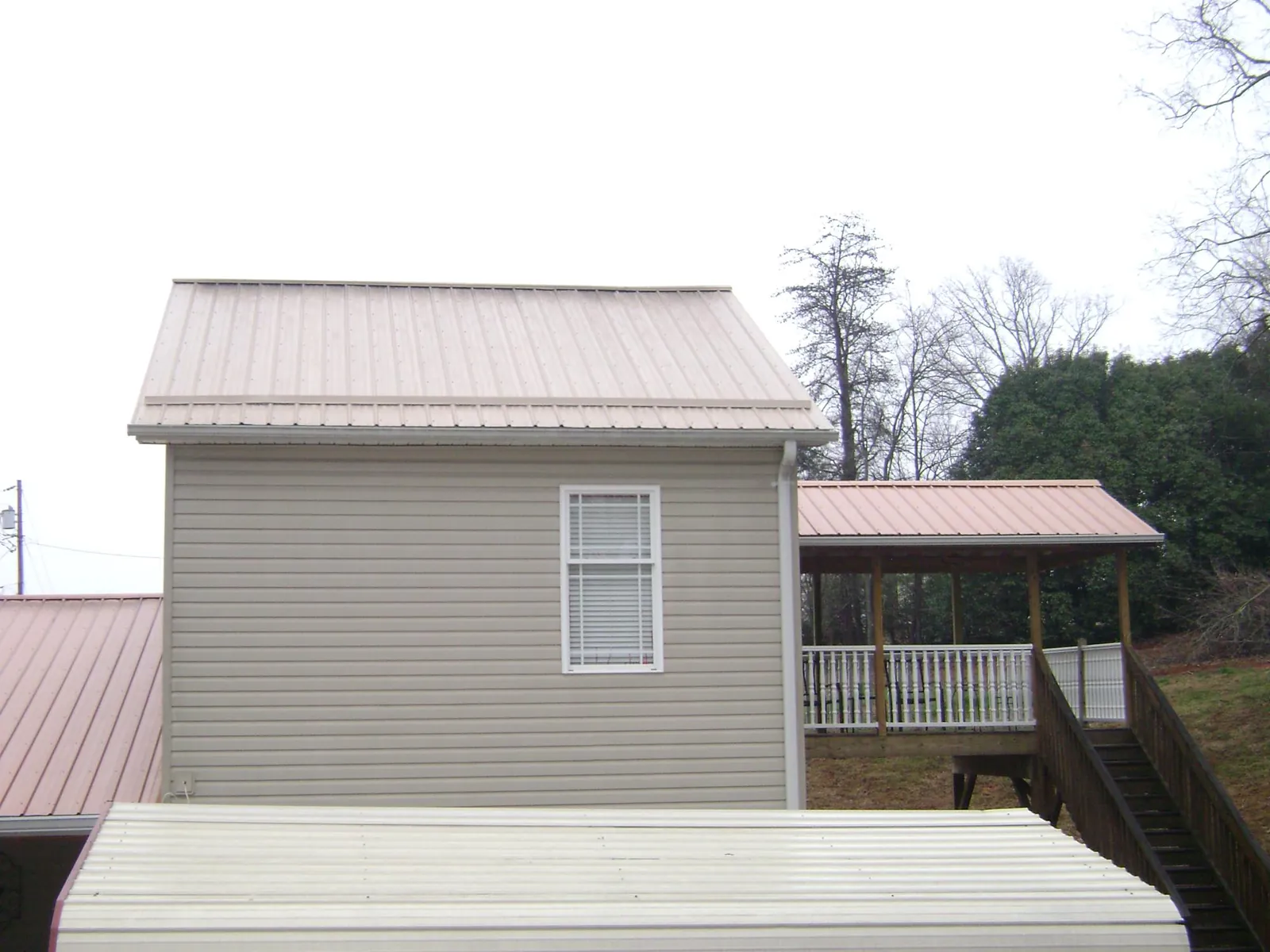 Tan metal roofs on a two story addition and attached porch, from a Roof Replacement job in Paint Lick