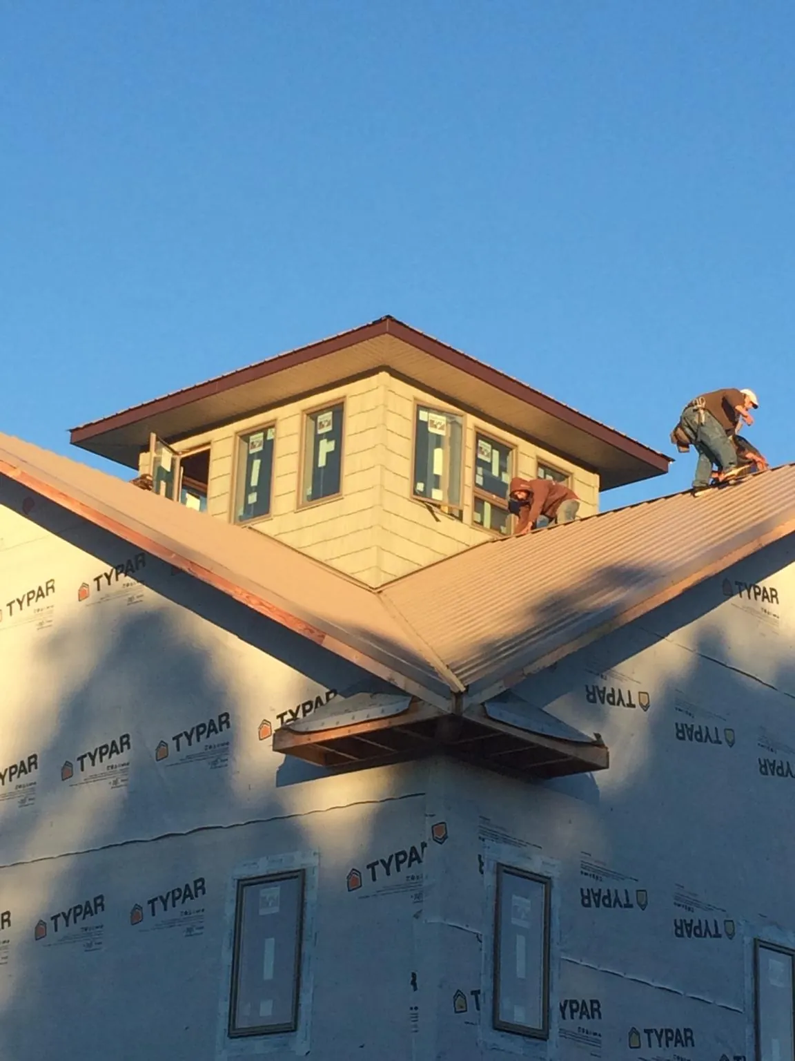 Roofers working around a rooftop cupola on a new metal roof at sunset — Roof Waterproofing in Paint Lick by Roofing Brothers